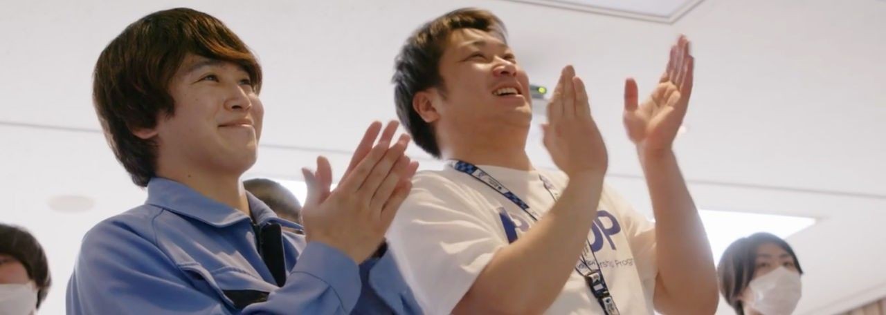 Group of people standing and clapping in a well-lit room.